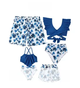 Flat lay of family matching swimsuits with blue palm tree print on white background