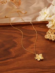 Detail of a golden flower pendant necklace on a luxury silk and wood background