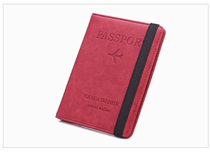 Detail of slim dark red faux leather passport holder with elastic closure and travel embossing
