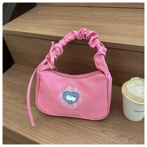 Detail of pink shoulder bag with ruffled handle and rabbit heart embroidery patch