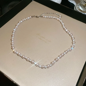 Detail of elegant white pearl necklace with sparkling diamond-set spacers in a gift box