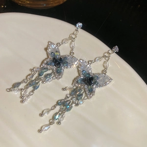 Détail des boucles d'oreilles papillon avec cristaux scintillants et glands bleu marine