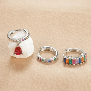 Detail view of silver drop earrings set with colorful zircon on champagne silk fabric