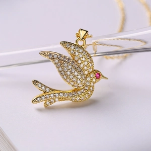 Collar con colgante de pájaro dorado con piedras brillantes sobre fondo de libro