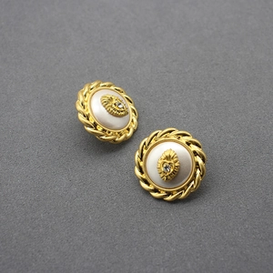 Close-up of vintage gold studs with twisted borders, shell inlay and heart rhinestones
