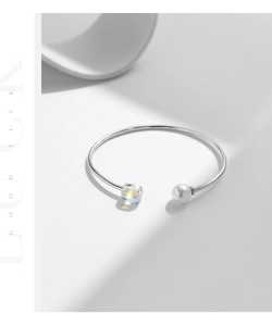 Detail of silver S925 open bracelet featuring a glowing moonstone and a lustrous pearl