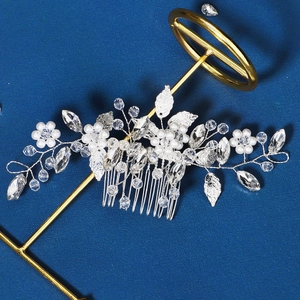 Detailed view of bridal hair comb with silver pearls and crystal flowers on a stand
