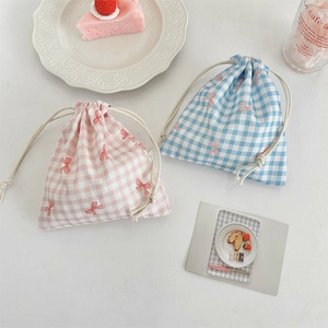 Close-up of pink and blue plaid drawstring storage bags with cute red bow patterns