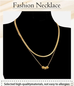 Detail of gold double-layered necklace featuring a flat snake chain and lucky beads