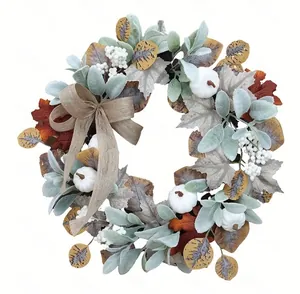 Detailed view of white faux pumpkins and burlap bow on an autumn leaf wreath