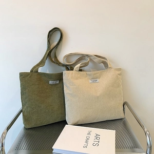 Artistic display of olive and beige corduroy tote bags on a metal chair in a soft setting