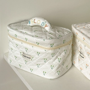Détail de la trousse de maquillage matelassée crème avec motifs cerises et broderie