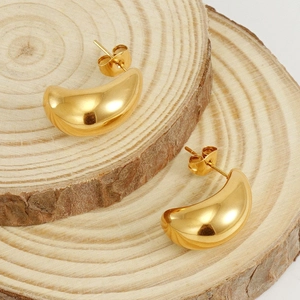 Polished 18K gold plated titanium steel crescent stud earrings on a natural wood slice
