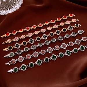 Gros plan de bracelets fleurs vintage sertis de strass colorés sur fond de soie
