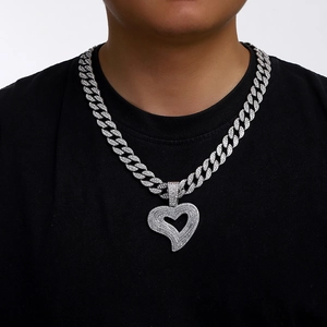 Close-up of a silver Cuban chain necklace featuring a rhinestone-paved heart pendant