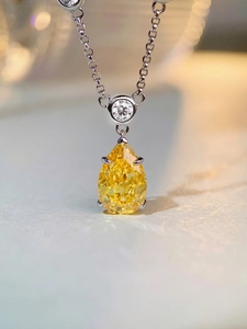 Macro shot of a pear-shaped yellow gemstone pendant with silver bubble chain