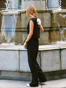 Outdoor-Ansicht eines Sets aus schwarzem ärmellosem Crop-Top und weiter Leinenhose