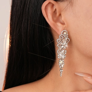 Close-up of luxury silver drop earrings with floral rhinestones and long tassels on a model