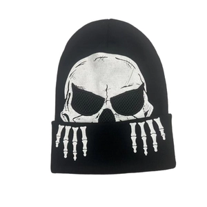 Detail view of black knit beanie featuring white skull print and skeleton hand bone pattern