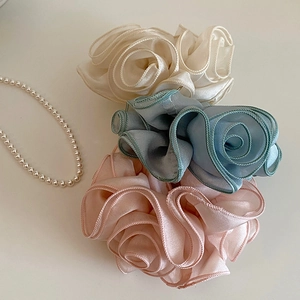 Three elegant fabric rose hair scrunchies in cream, blue, and pink for low ponytails