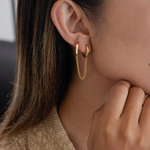 Gros plan sur des boucles d'oreilles double anneau en acier doré 18K avec chaîne et zircon
