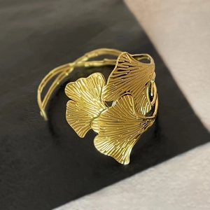 Detail of golden ginkgo leaf cuff bracelet showing intricate vein textures on a dark base