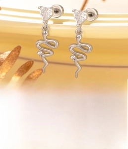Vue macro des boucles d'oreilles serpent argent avec zircon coeur et cristaux étincelants