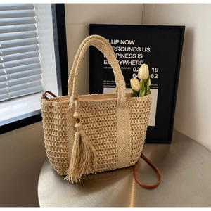 Detailed close-up of straw tote bag with elegant tassel and woven texture detail