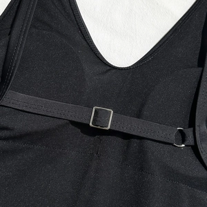 Detail of adjustable straps with silver metal buckles on a black backless swimsuit