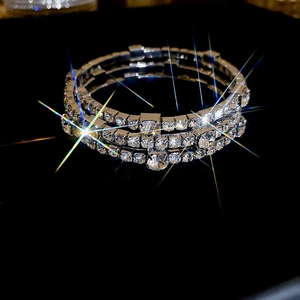 Three-layer silver rhinestone bracelet with glittering crystals on a black reflective surface