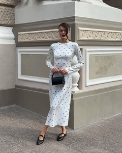 Close-up detail of white long-sleeve dress with elegant black polka dot pattern