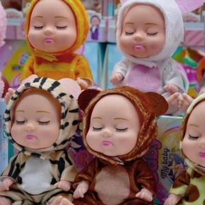 Close-up of assorted 5-inch sleeping baby dolls in colorful plush animal onesies