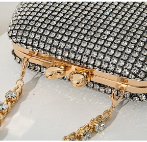 Close-up of sparkling silver rhinestones on evening clutch with golden chain detail