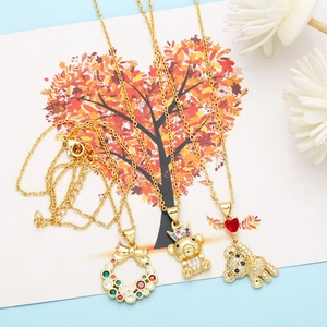 Detailed view of three gold necklaces with colorful zircon heart and bear pendants