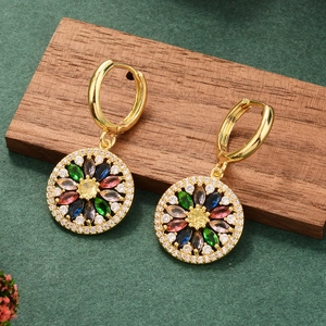 Detailed shot of gold earrings with multicolored stones and zircons on textured background