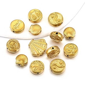 Detailed view of assorted gold stainless steel beads with sun and cat patterns