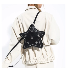 Detail of black PU leather star-shaped crossbody bag with silver rivets and metal chain