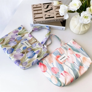 Flat lay of pink and purple tulip print canvas handbags with stylish fashion magazine decor