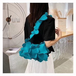 Detail of blue shoulder bag featuring 3D floral petal design and textured layers