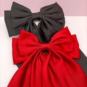 Close-up of red and black satin bow hair clips with elegant long ribbons in detail