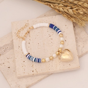 Bohemian clay bead bracelet with white pearls and a large gold heart charm in top view