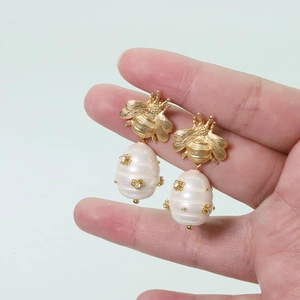 Detail of bee earrings with white baroque pearls and crystal flower accents