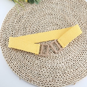 Close-up of a yellow woven elastic belt featuring a geometric gold metal buckle