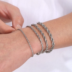 Detail showing four silver twisted chain bracelets of different thicknesses on wrist