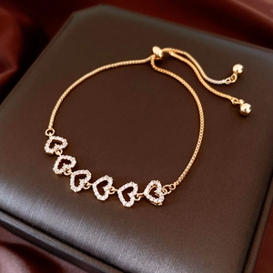 Detail of adjustable gold-plated bracelet with cubic zirconia heart charms on silk