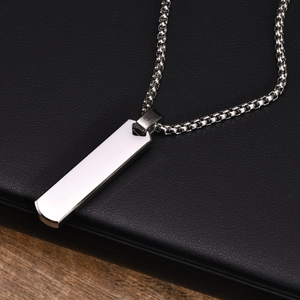 Silver vertical bar necklace on black notebook showing polished steel texture and O-chain