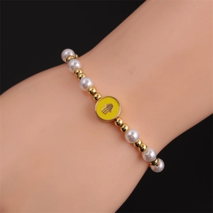 Detailed shot of Hamsa hand charm bracelet with white pearls and gold metal beads