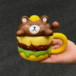 Close-up of creative ceramic burger mug with cute brown bear head lid and matching spoon