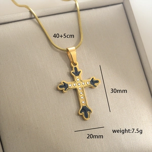 Détail du pendentif croix dorée avec émail noir et zircon sur une chaîne serpent fine