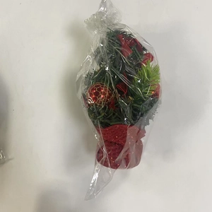 Detailed view of mini Christmas tree in plastic bag with red bow and bauble ornaments